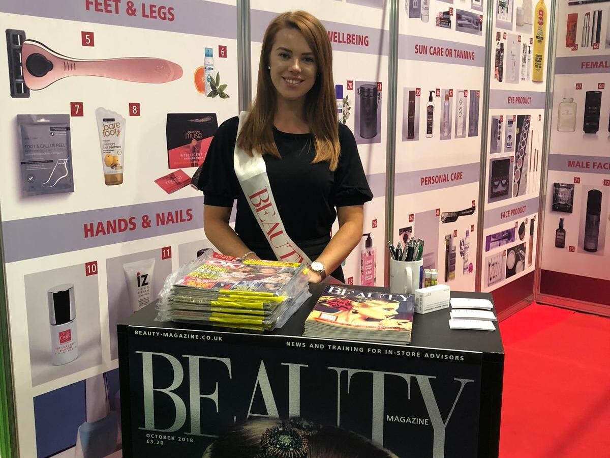 Magazine exhibition staff member working at an exhibition stand at a beauty event