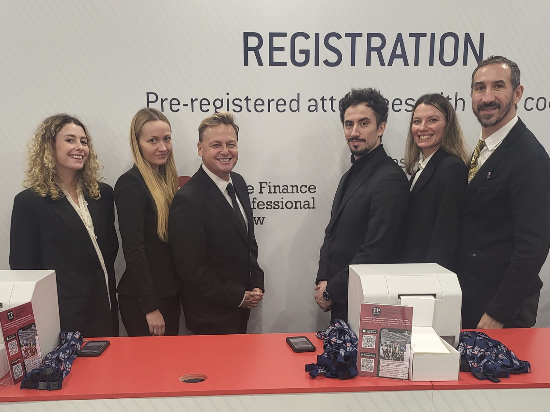 London exhibition registration staff lined up behind a reception desk, all wearing formalwear